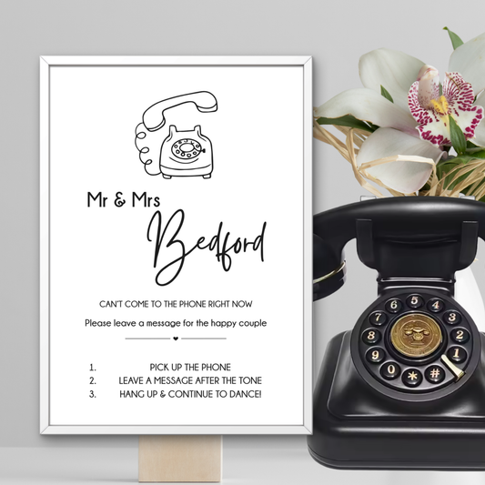 Vintage black rotary phone with a framed sign on a gray background